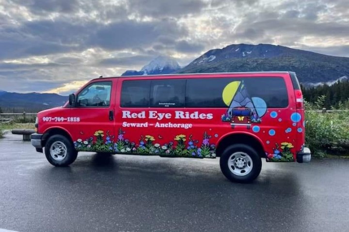 Red van with graffiti art parked on a mountain road.