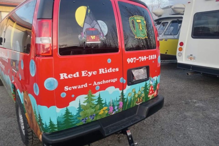 Colorful van with nature-themed mural and 'Red Eye Rides' text parked among other vehicles.