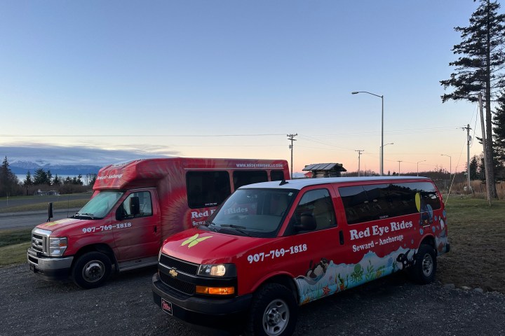 Two Red Eye Rides vans parked on roadside at sunset.