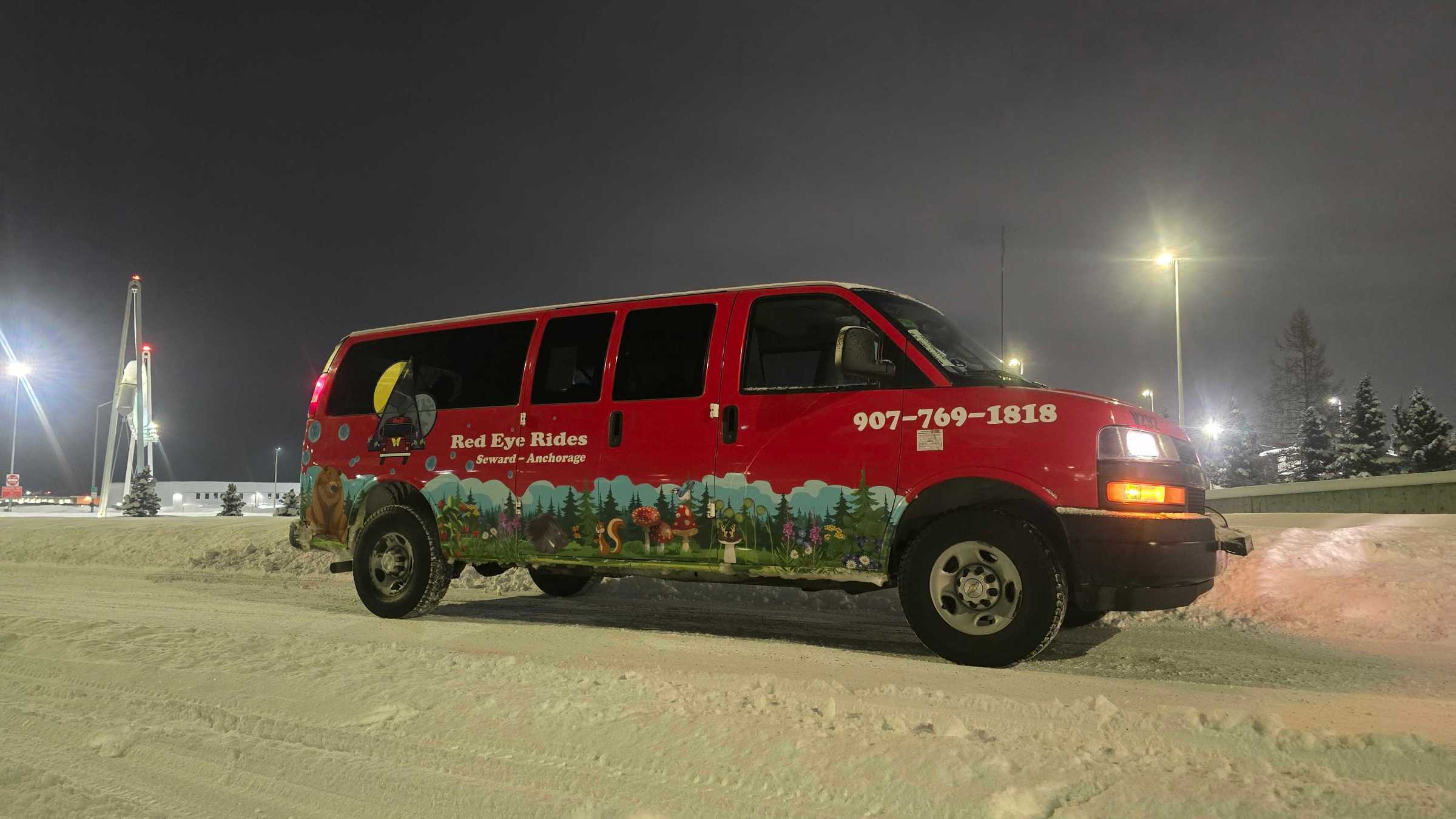 Red van with decorative graphics parked on snowy street at night.